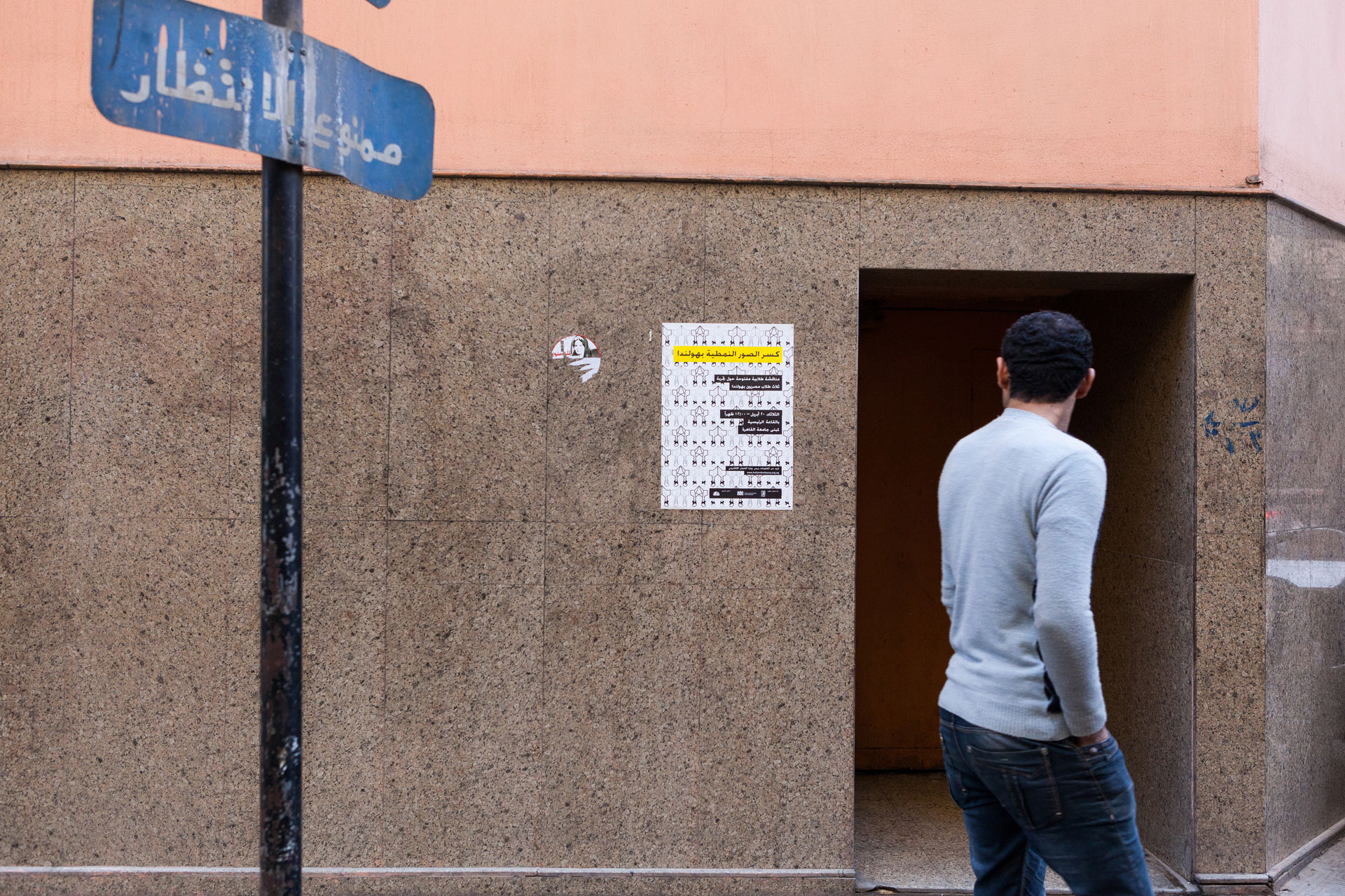 Image displaying a photograph of the poster created for the event to launch the Connecting Identities publication. pasted on a wall in the streets of Cairo, Egypt.